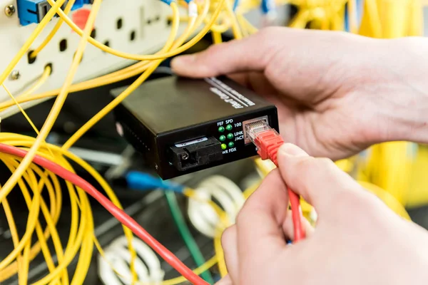 Network engineer working in server room. Connecting network cables to switches