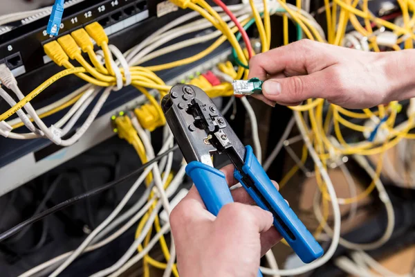 Network engineer working in server room. Connecting network cables to switches