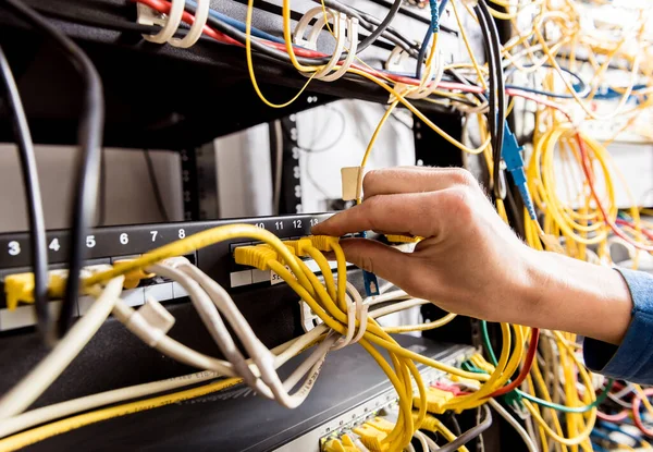 Engenheiro de rede a trabalhar na sala de servidores. Conectando cabos de rede aos switches — Fotografia de Stock