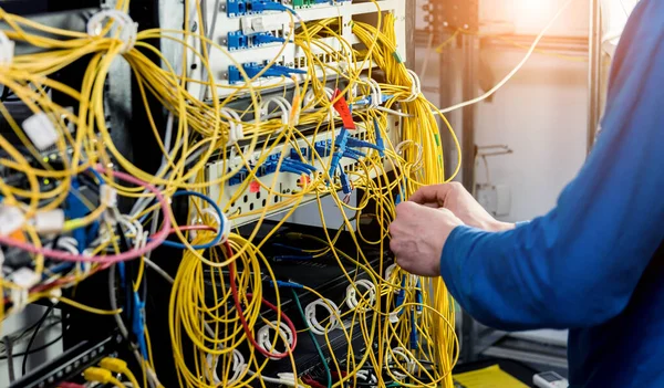 Engenheiro de rede a trabalhar na sala de servidores. Conectando cabos de rede aos switches — Fotografia de Stock