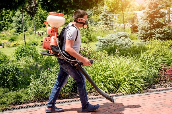 Trädgårdsmästare i skyddsmask och glasögon sprutar giftiga bekämpningsmedel träd — Stockfoto