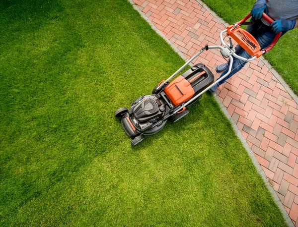 庭師は芝生を刈る。ランドスケープデザイン。緑の草の背景 — ストック写真