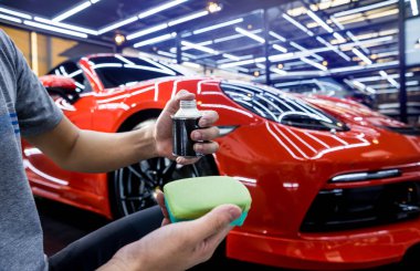 Araba servisi çalışanı bir araba detayına nano kaplama uyguluyor.