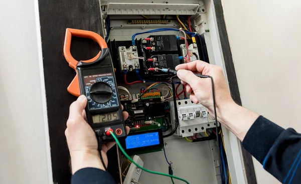 The man is repairing the switchboard voltage with automatic switches. — Stock Photo, Image