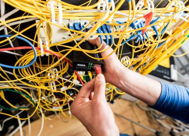 Sunucu odasında çalışan ağ mühendisi. Ağ kabloları anahtarlara bağlanıyor