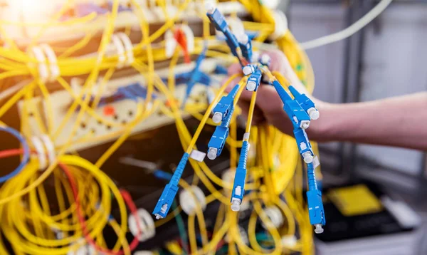 Engenheiro de rede a trabalhar na sala de servidores. Conectando cabos de rede aos switches — Fotografia de Stock