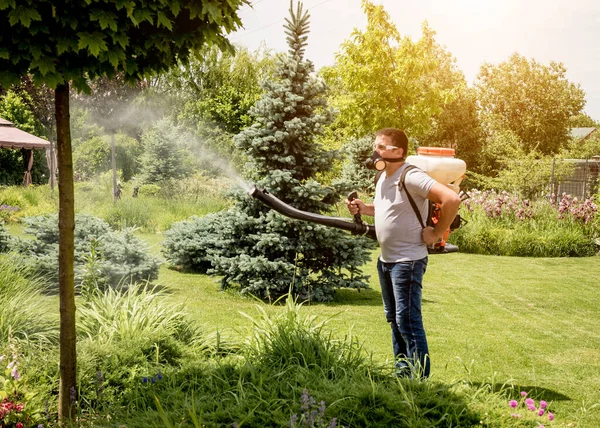 Gärtner mit Schutzmaske und Brille versprüht giftige Pestizide — Stockfoto