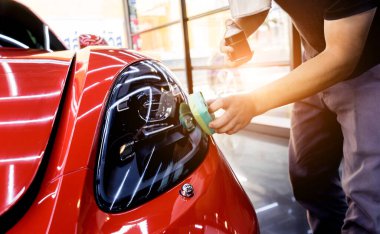 Araba servisi çalışanı bir araba detayına nano kaplama uyguluyor.