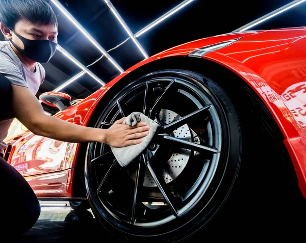 Trabajador de servicio de coche puliendo ruedas de coche con tela de microfibra. — Foto de Stock