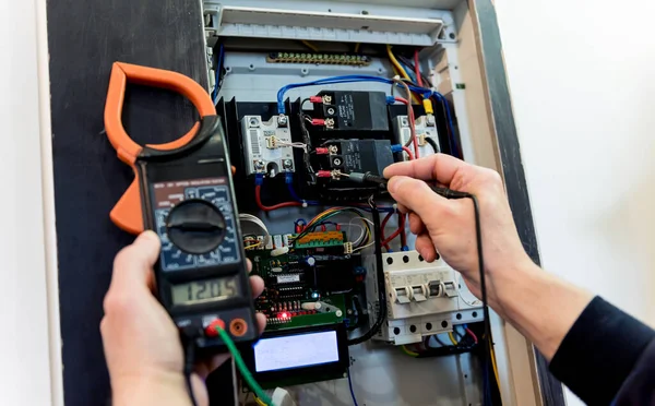 El hombre está reparando el voltaje de la centralita con interruptores automáticos . —  Fotos de Stock