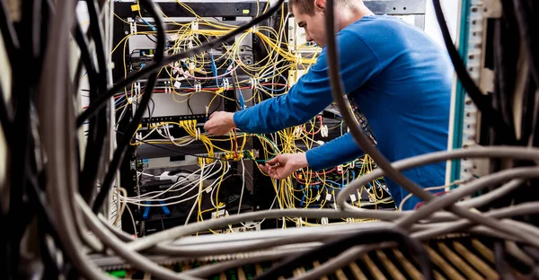 Inżynier sieci pracujący w serwerowni. Podłączanie kabli sieciowych do przełączników — Zdjęcie stockowe