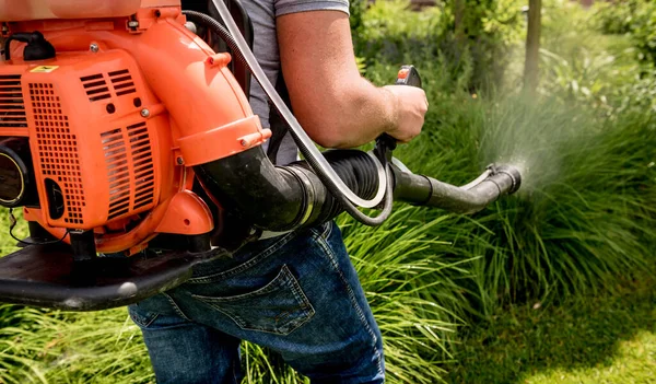 Trädgårdsmästare i skyddsmask och glasögon sprutar giftiga bekämpningsmedel träd — Stockfoto