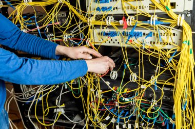 Sunucu odasında çalışan ağ mühendisi. Ağ kabloları anahtarlara bağlanıyor