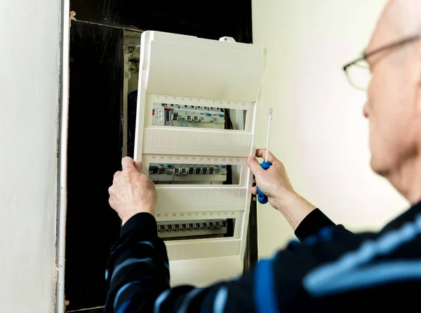 De man repareert de schakelbordspanning met automatische schakelaars. — Stockfoto