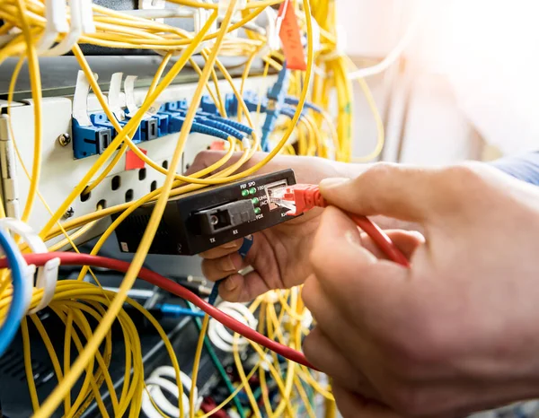 Síťový inženýr pracující v serverovně. Připojování síťových kabelů k přepínačům — Stock fotografie