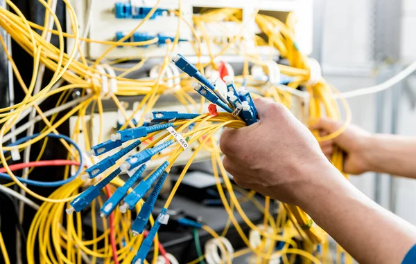 Network engineer working in server room. Connecting network cables to switches