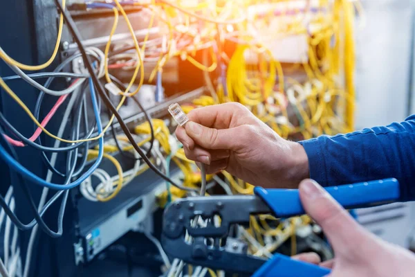 Network engineer working in server room. Connecting network cables to switches