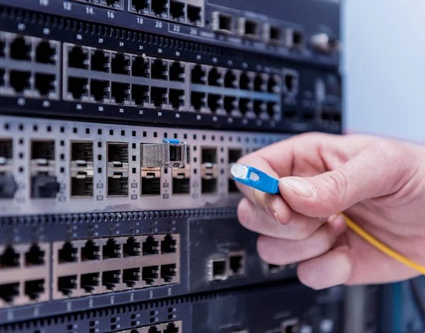 Network engineer working in server room. Connecting network cables to switches