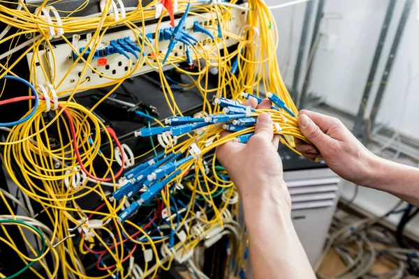 Network engineer working in server room. Connecting network cables to switches