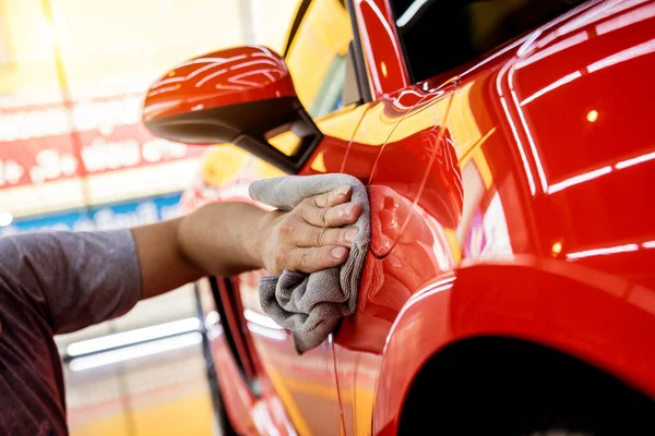 Autoservice-Mitarbeiter poliert Auto mit Mikrofasertuch. — Stockfoto