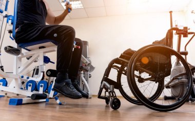 Tekerlekli sandalyeden ayrı olarak egzersiz yapan engelli bir adam..