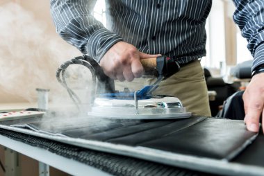 Tasarımcı koltuk kılıflarını diker. İnsan işi için demir kullanır..