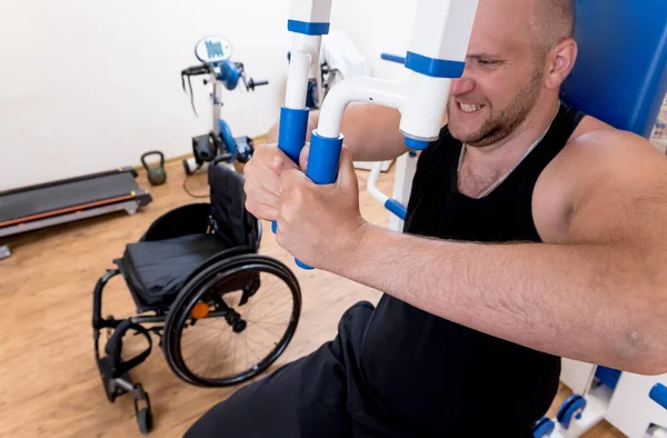 Behinderter Mann macht Kraftübungen getrennt vom Rollstuhl. — Stockfoto