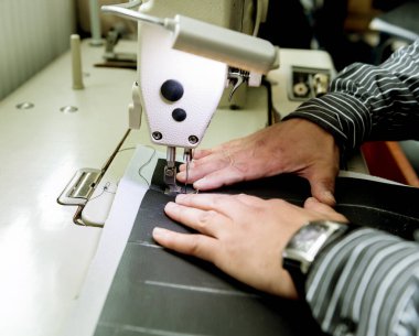 Tasarımcı koltuk kılıflarını diker. Adam işi için dikiş makinesi kullanıyor..