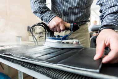 Tasarımcı koltuk kılıflarını diker. İnsan işi için demir kullanır..