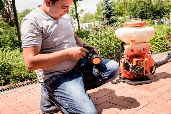 Giardiniere in maschera protettiva e occhiali spruzzando pesticidi tossici alberi — Foto Stock