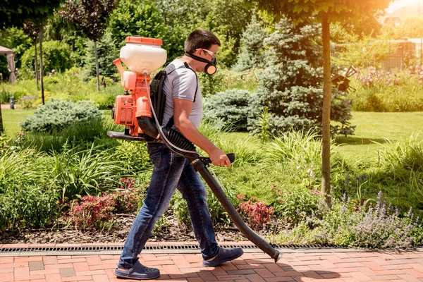 Tuinman in beschermend masker en bril sproeiend giftige pesticiden bomen — Stockfoto