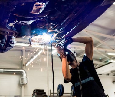 Koruyucu maskeli kaynakçı araba tamircisi. Servis İstasyonu