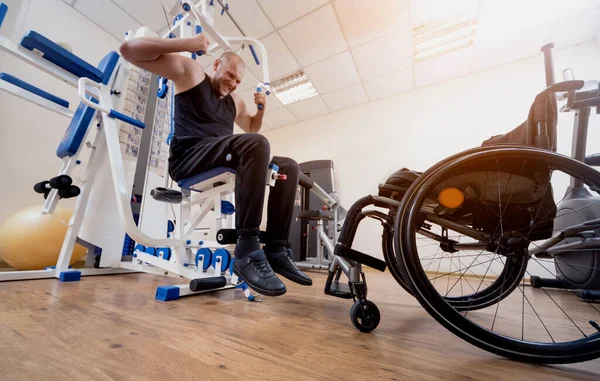 Gehandicapte man die krachtoefeningen doet los van de rolstoel. — Stockfoto