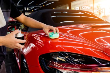 Araba servisi çalışanı bir araba detayına nano kaplama uyguluyor.