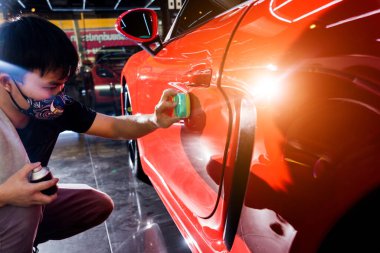 Car service worker applying nano coating on a car detail clipart