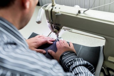 Tasarımcı koltuk kılıflarını diker. Adam işi için dikiş makinesi kullanıyor..