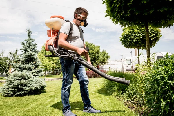 Giardiniere in maschera protettiva e occhiali spruzzando pesticidi tossici alberi — Foto Stock