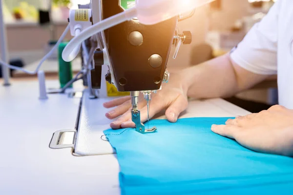 डिझायनर टेलर ड्रेस शिवून टाकतो. स्त्री त्याच्या कामासाठी शिवणकाम मशीन वापरते . — स्टॉक फोटो, इमेज