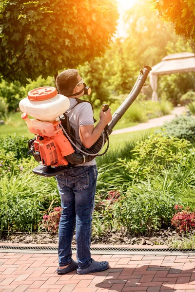 Tuinman in beschermend masker en bril sproeiend giftige pesticiden bomen — Stockfoto