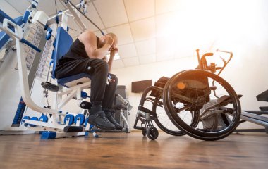 Tekerlekli sandalyeden ayrı olarak egzersiz yapan engelli bir adam..