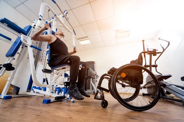 Zdravotně postižený muž dělá silová cvičení oddělená od invalidního vozíku. — Stock fotografie