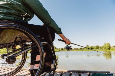 Tekerlekli sandalyede balık tutan engelli bir genç..