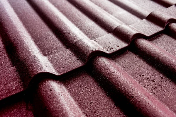 Red metallic roof tiles background with drops of water.