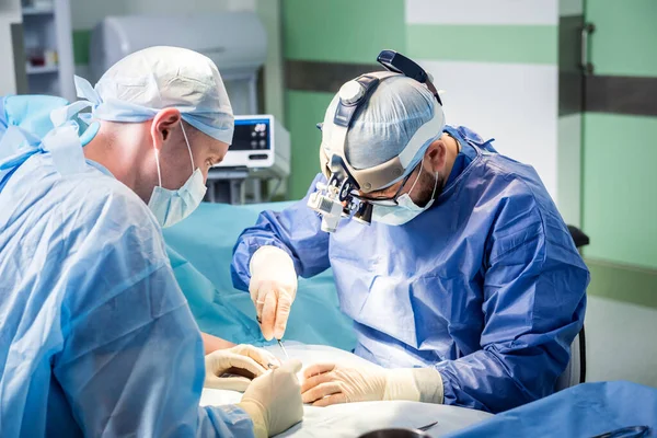 Chirurdzy na sali operacyjnej próbują uratować dłoń pacjentów.. — Zdjęcie stockowe