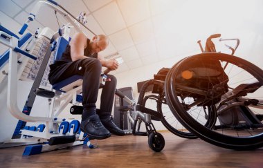 Tekerlekli sandalyeden ayrı olarak egzersiz yapan engelli bir adam..