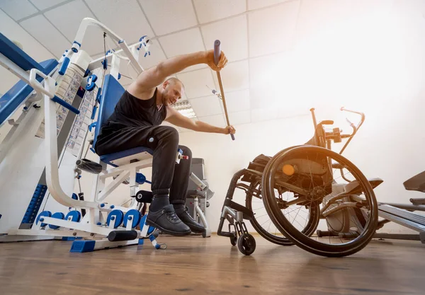 Zdravotně postižený muž dělá silová cvičení oddělená od invalidního vozíku. — Stock fotografie