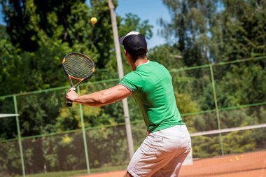 Sahada tenis oynayan genç bir atletik..