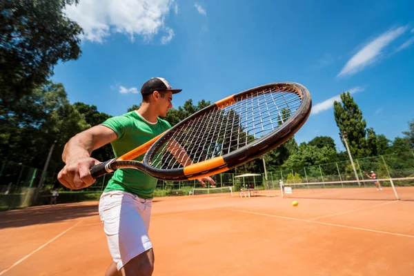 Młody sportowiec gra w tenisa na korcie. — Zdjęcie stockowe
