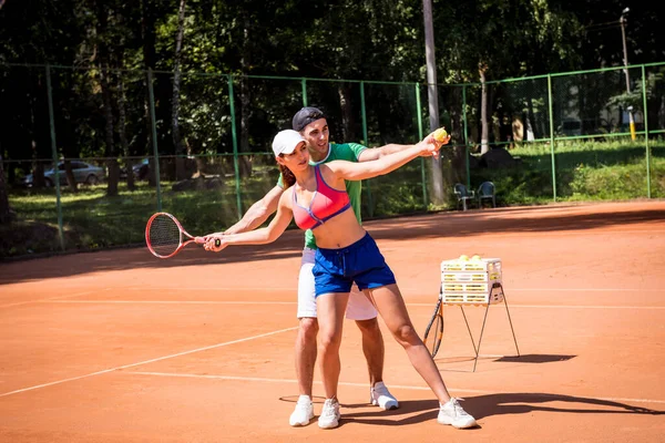 Mladá atletka hraje tenis se svým trenérem. — Stock fotografie