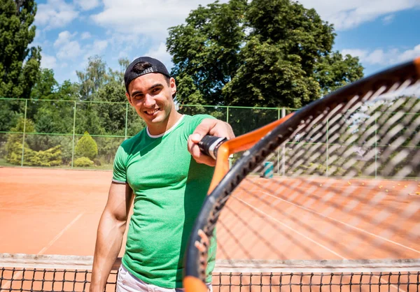 Porträtt av ung atletisk man på tennisbana. — Stockfoto